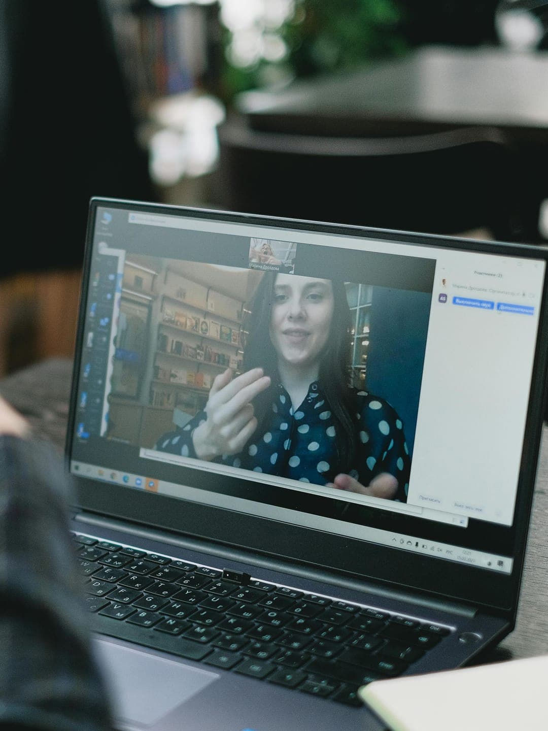 Happy ethnic woman sitting at table with laptop