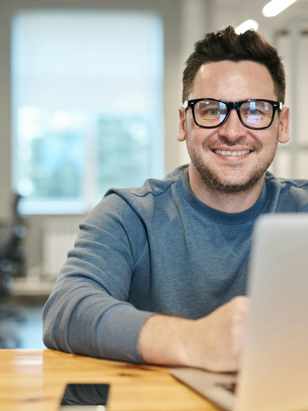 Happy ethnic woman sitting at table with laptop
