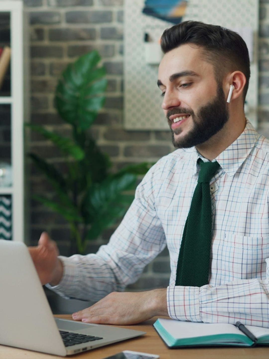 Happy ethnic woman sitting at table with laptop