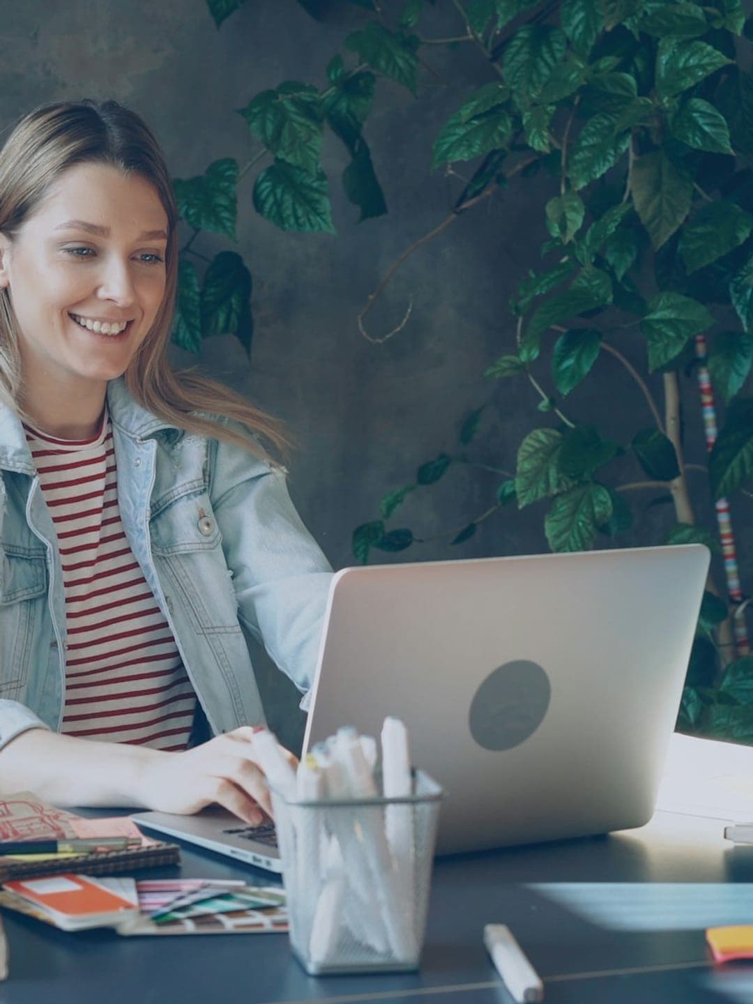 Happy ethnic woman sitting at table with laptop
