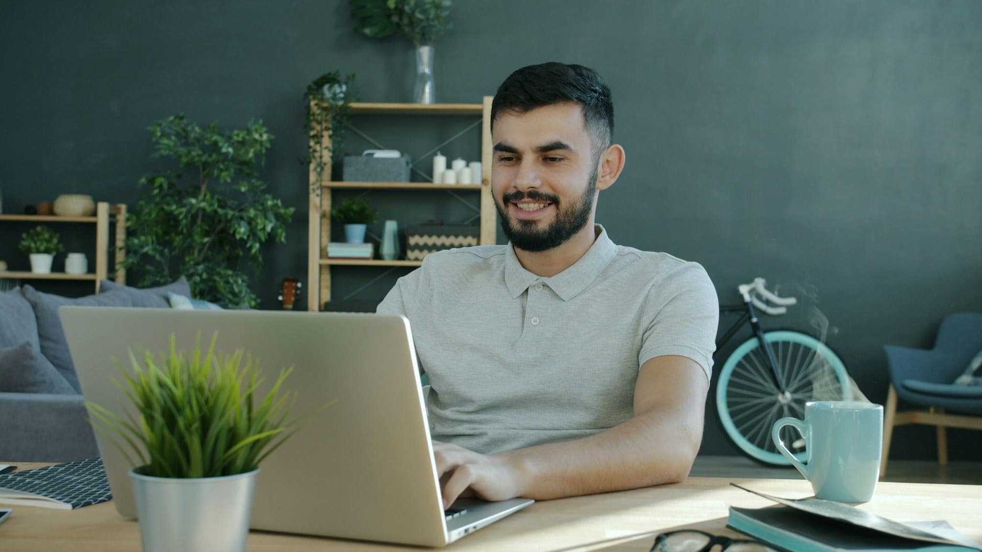 Happy ethnic woman sitting at table with laptop